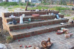 Photo of brick steps leading to the foundation of a home that was destroyed in the storm. A shrine is set up on the stairs in memory of those lost in Katrina.