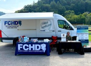 Justin Apperson sits in front of a mobile legal clinic conducting outreach at a harm reduction event