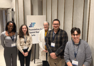 Picture of Equal Justice Works staff and OCRP Fellow attendees of the FORE Convening, they stand in front of a sign reading "Foundation for Opioid Response Efforts"