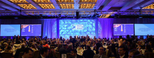 photo of ballroom with blue lights on stage and Equal Justice Works logo