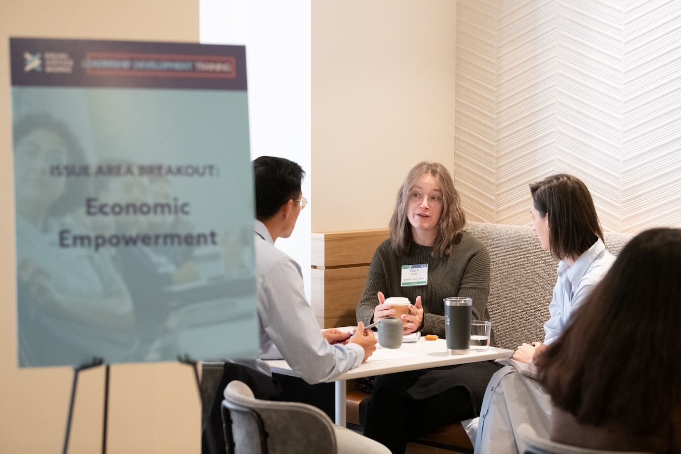 Fellows speak in a small group at Leadership Development Training. Next to them, a sign reads: issue area breakout: economic empowerment