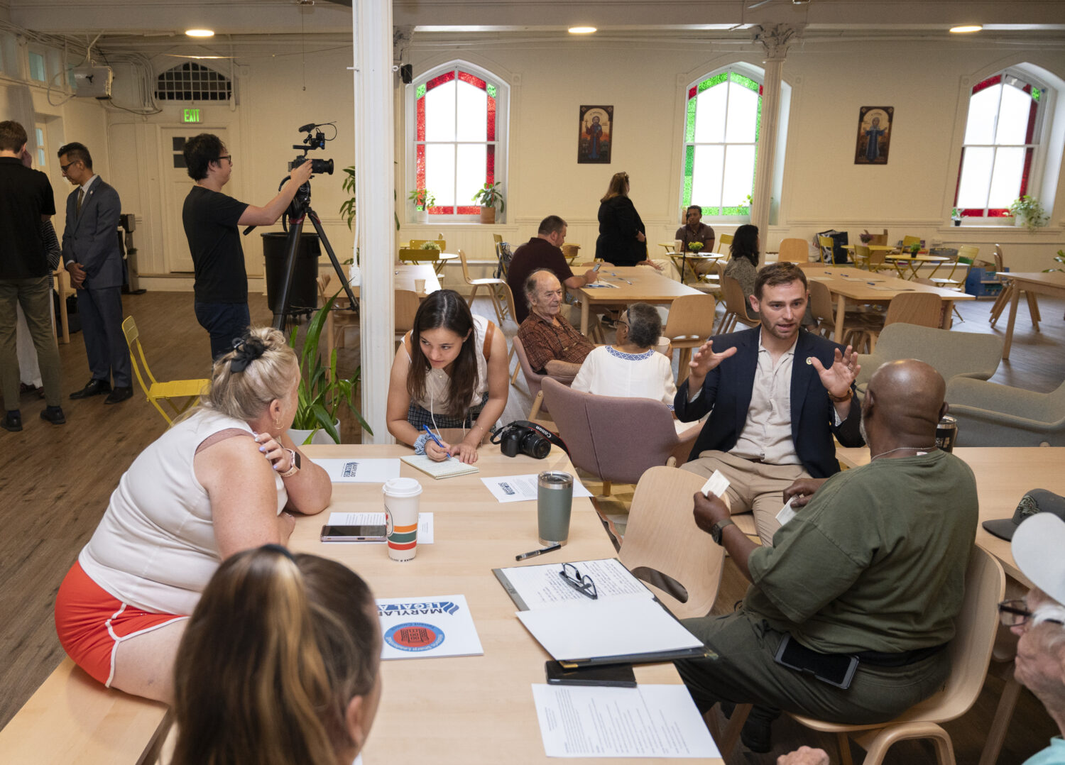 Photo of tenant advocacy group for Sharp Leadenhall Apartments. Zac Blanchard sits at a table and discusses the lawsuit with tenants.